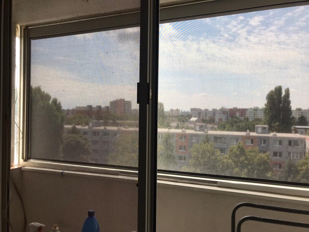 Pohľad zvnútra bytu cez screenovú roletu na balkóne v Petržalke